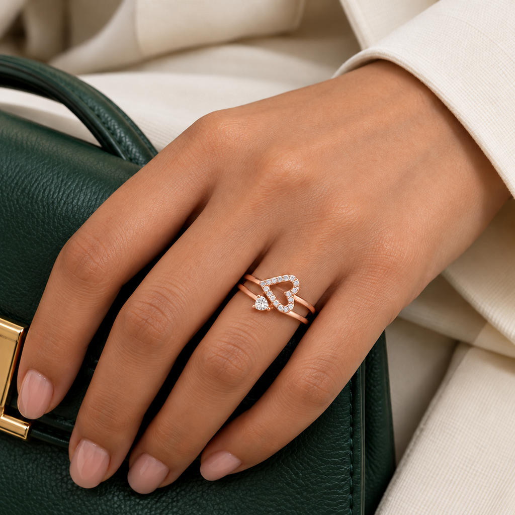 Adeline rose gold plated double-band heart ring worn on a model's hand beside a cream tailored sleeve