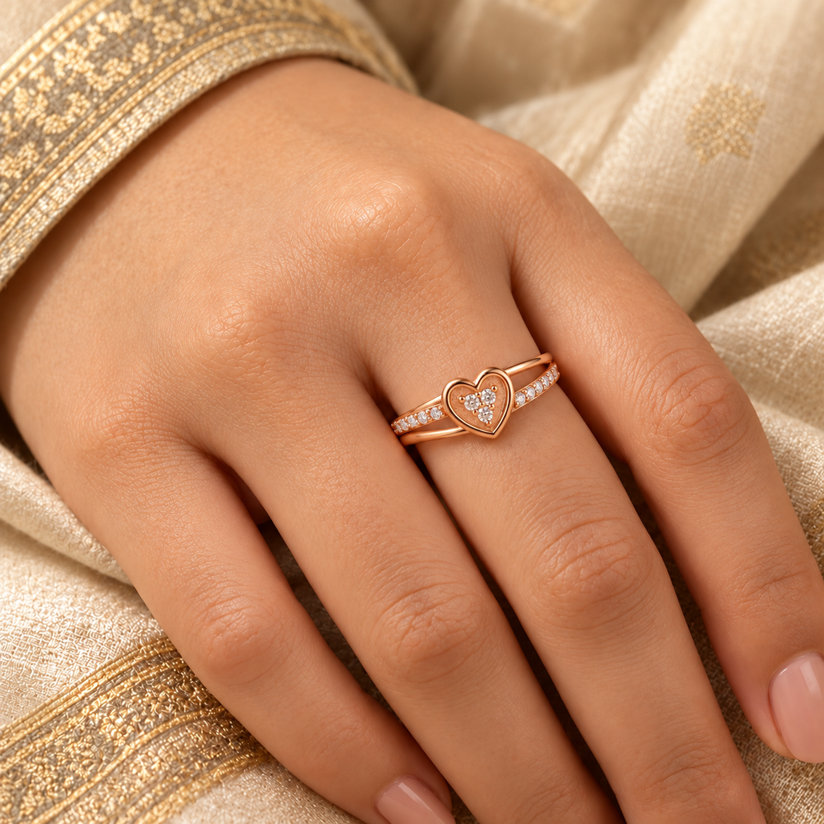 Amorette rose gold plated heart ring worn on a model's hand against an elegant champagne silk saree