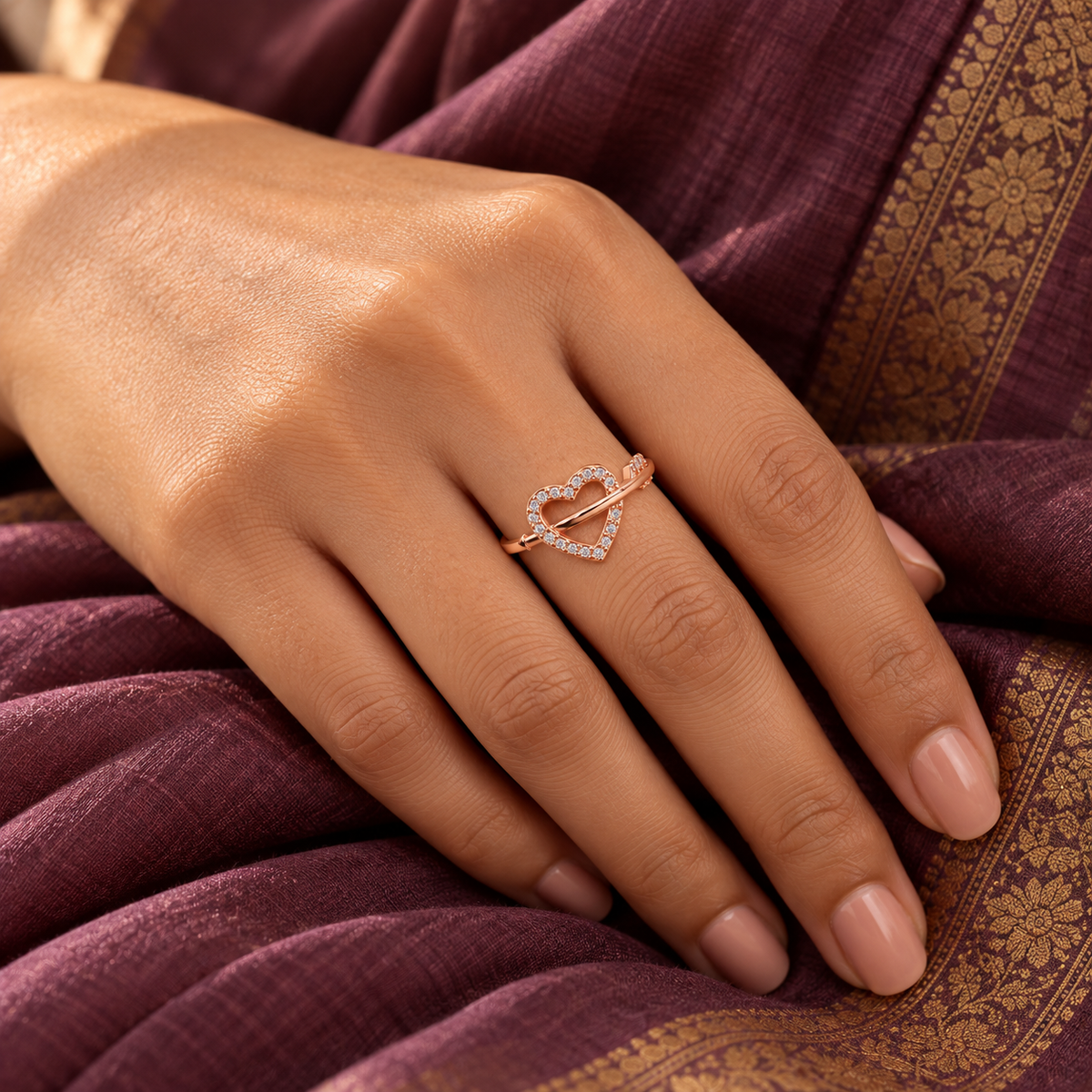 Evermore rose gold plated open-heart ring worn on a model's hand with a plum silk saree