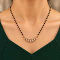 Sitara Mangalsutra seven clear teardrops and black-bead chain worn with a forest-green professional dress