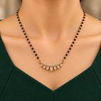 Sitara Mangalsutra seven clear teardrops and black-bead chain worn with a forest-green professional dress
