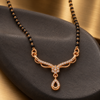 Angled view of Aarohi Mangalsutra on charcoal ceramic with a warm metallic background
