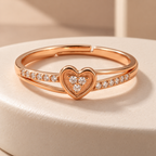 Amorette rose gold plated heart ring on an ivory ceramic plinth, showing its clear cluster and open layered band