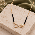 Ananta Mangalsutra infinity and leaf pendant viewed at an angle on ivory travertine