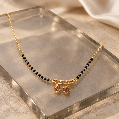 Anuraga twin-heart mangalsutra arranged on smoked glass at an oblique angle