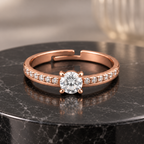 Elysian rose gold plated ring with a round clear centre and four prongs on black marble