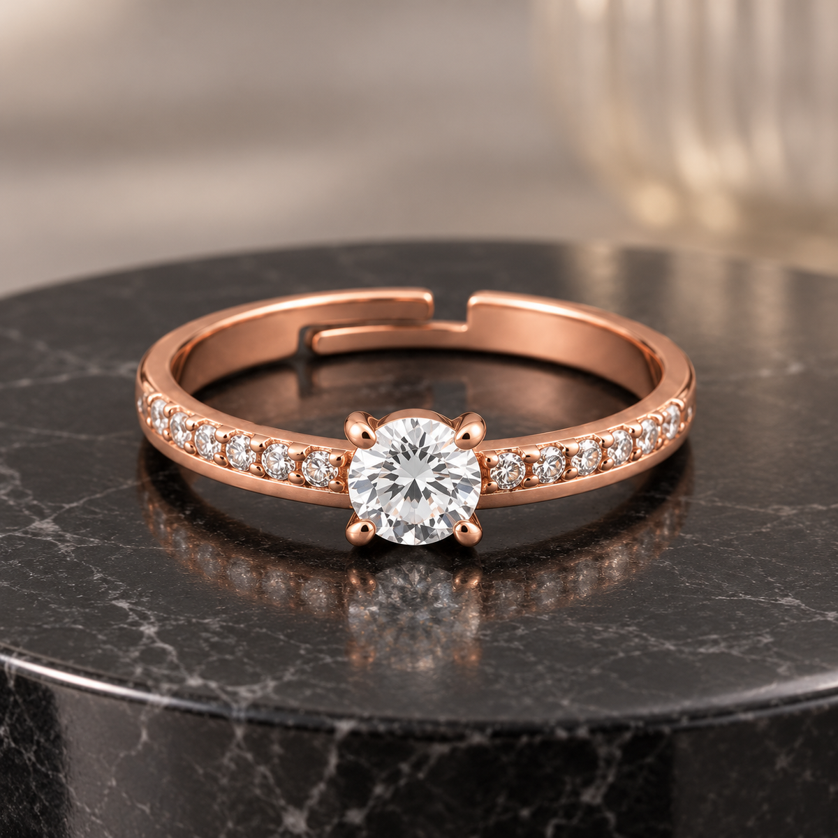 Elysian rose gold plated ring with a round clear centre and four prongs on black marble