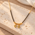 Kanakpriya twin-heart mangalsutra on pale travertine, photographed from an oblique angle