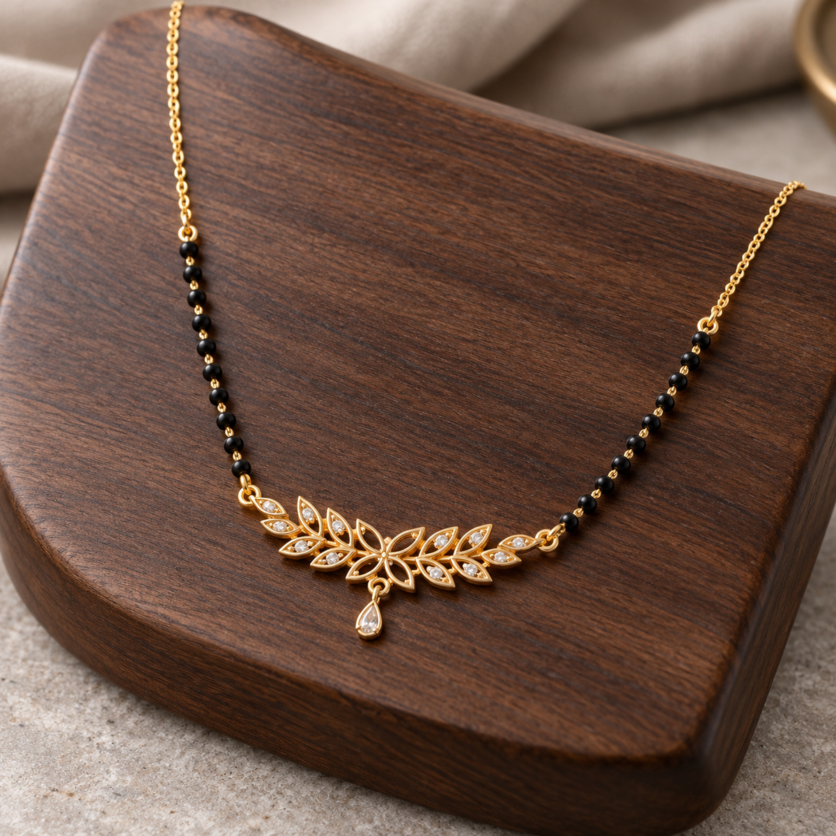 Madhavi floral mangalsutra on dark walnut wood, photographed from an oblique angle