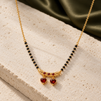 Ragini Mangalsutra with twin red heart drops photographed at an angle on ivory limestone