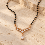 Saanvika Mangalsutra compact seven-stone pendant and hanging pear photographed at an angle on travertine