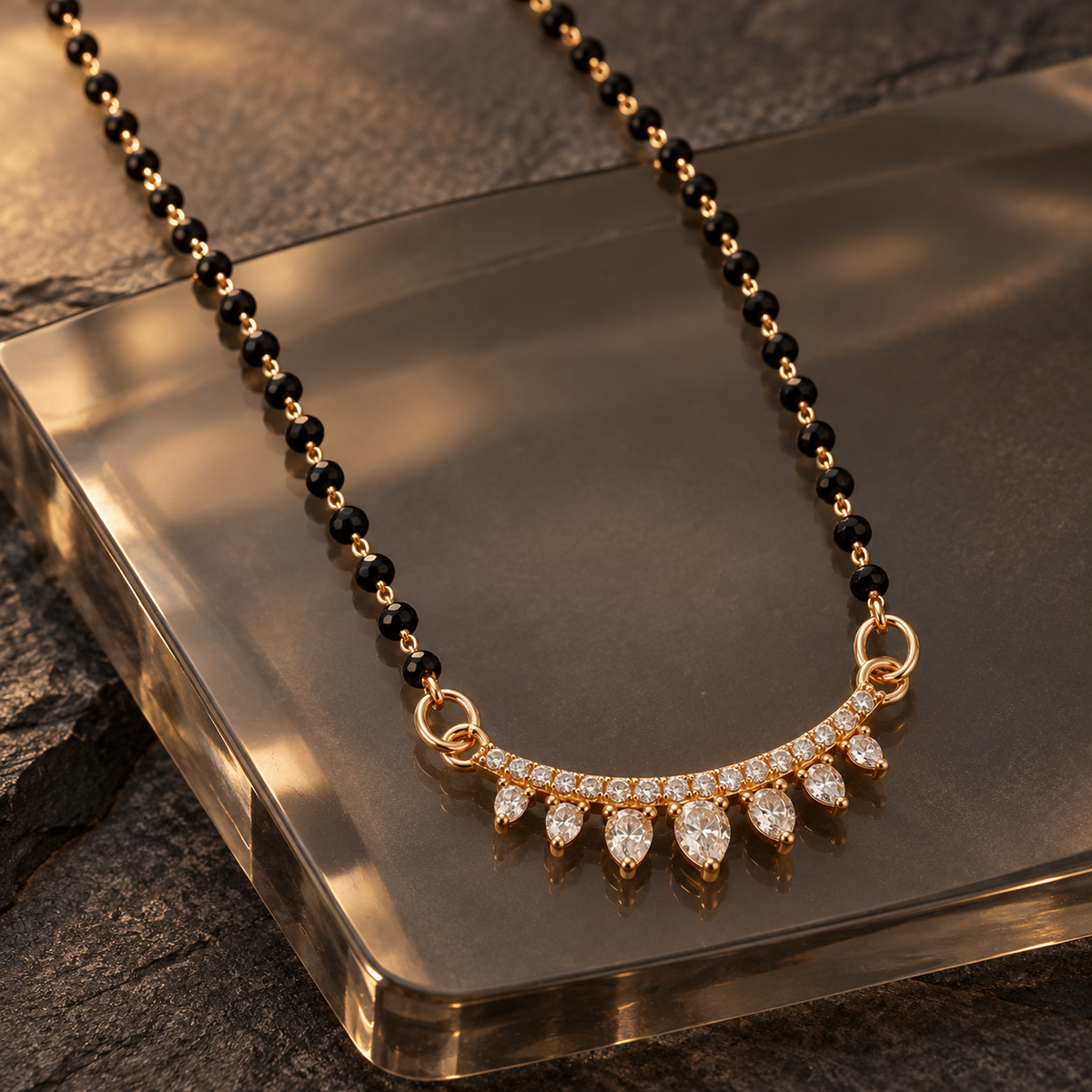 Sitara Mangalsutra seven graduated clear teardrops photographed at an angle on smoky glass