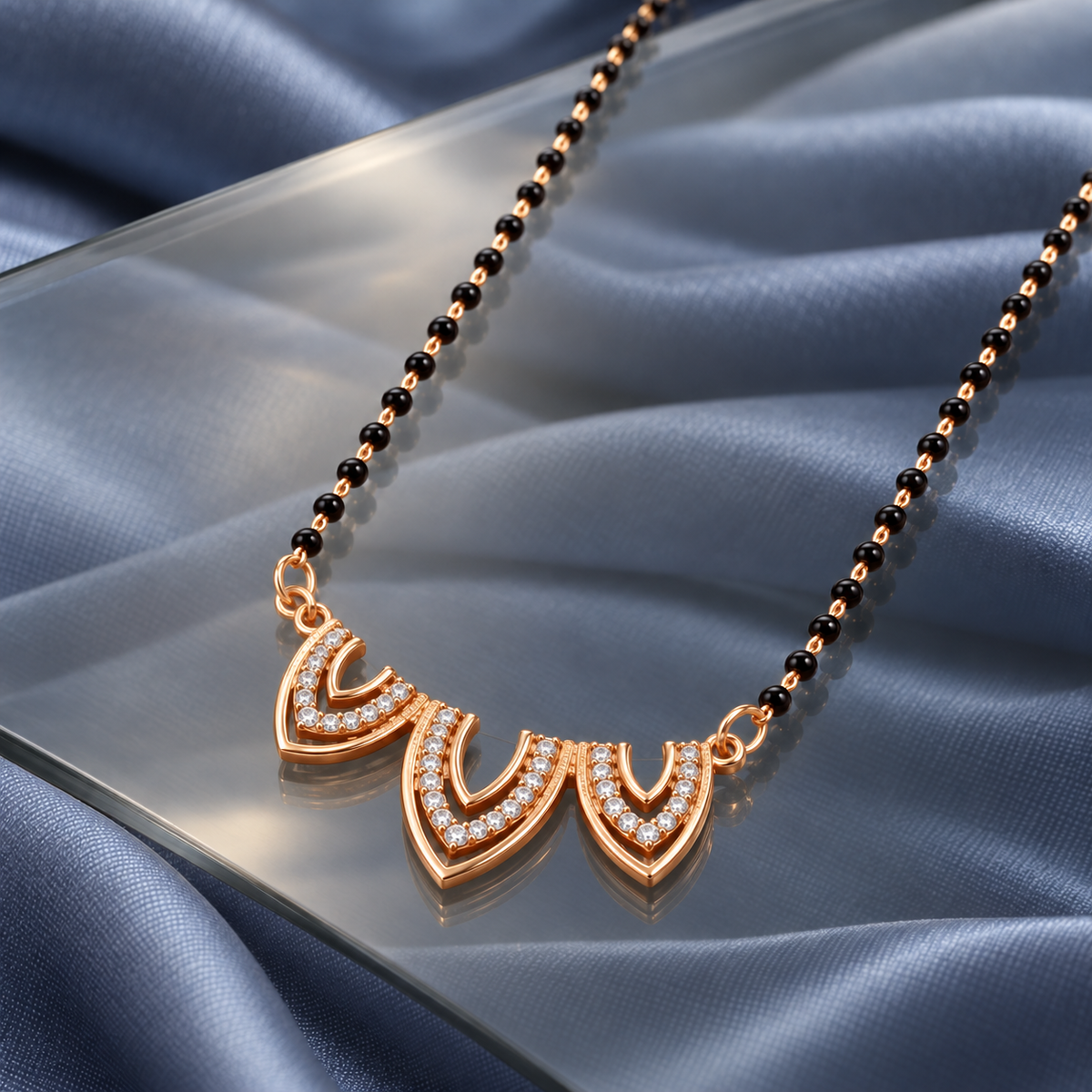 Angled view of Trishika Mangalsutra on smoky glass with blue-grey silk