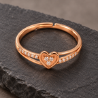 Amorette heart ring from a high angle on dark stone, showing the clear cluster, open band and adjustable back