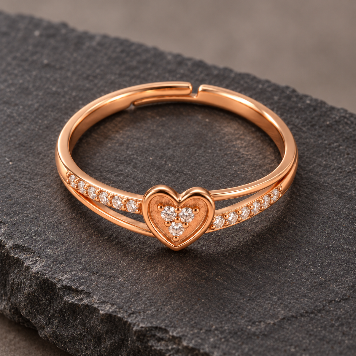 Amorette heart ring from a high angle on dark stone, showing the clear cluster, open band and adjustable back
