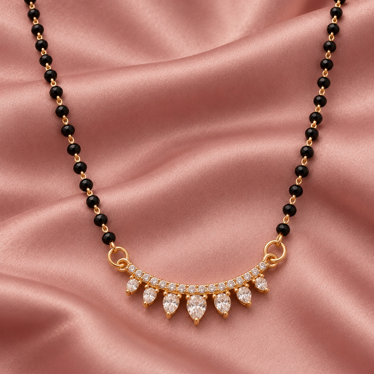 Overhead detail of Sitara Mangalsutra seven graduated clear teardrops on dusty-rose satin