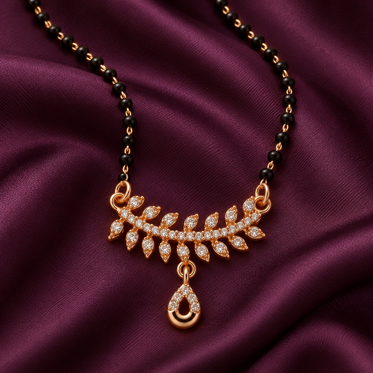 Close detail of Vanalika Mangalsutra leaf accents and open teardrop charm on aubergine silk