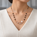 Astrielle Mangalsutra worn with an ivory woven V-neck dress, showing the pendant and black bead chain.