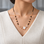 Clarion Mangalsutra worn with an ivory woven V-neck dress, showing the pendant and black bead chain.
