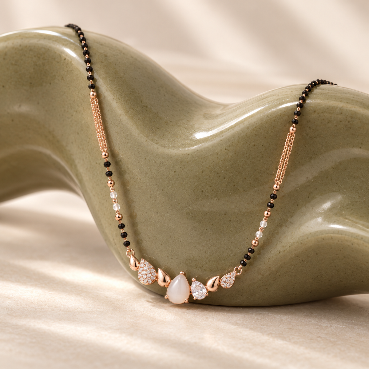 White pear-row mangalsutra on an olive ceramic sculpture