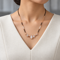 Isadora Mangalsutra worn with an ivory woven V-neck dress, showing the pendant and black bead chain.