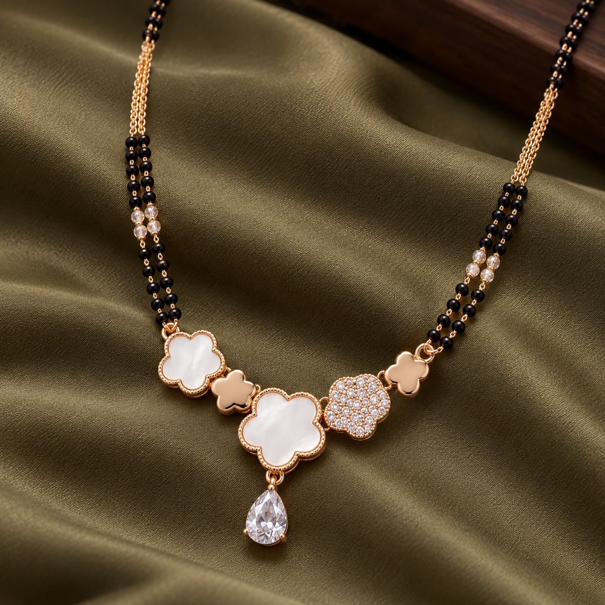 Close view of Liora white-inlay and pavé clovers on olive silk.