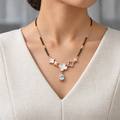 Maelle Mangalsutra worn with an ivory woven V-neck dress, showing the pendant and black bead chain.