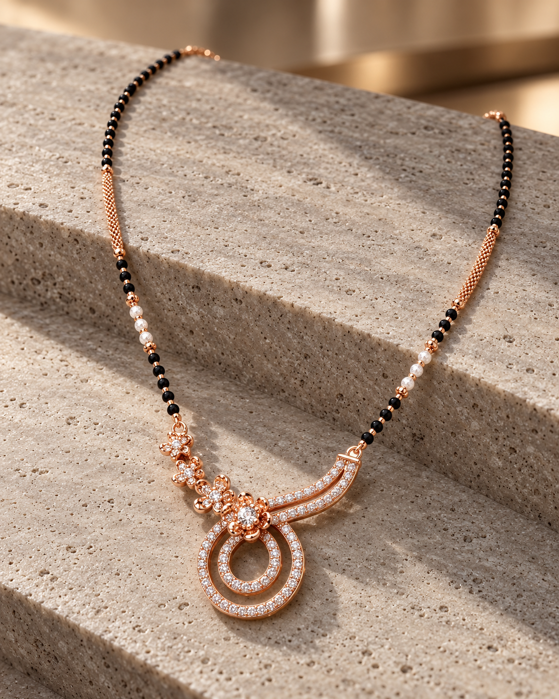 Mirelle Mangalsutra arranged on travertine at a three-quarter angle