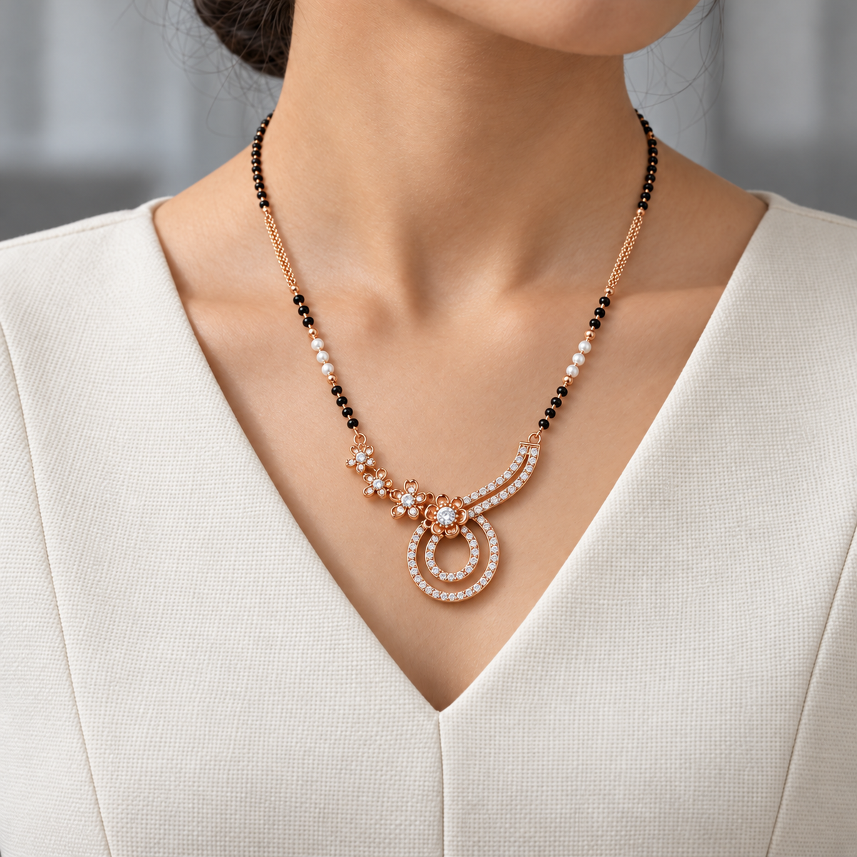 Mirelle Mangalsutra worn with an ivory woven V-neck dress, showing the pendant and black bead chain.