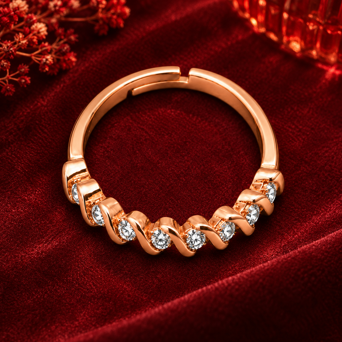 Ophelia Ring in rose gold, from a high angle on burgundy satin with warm festive bokeh