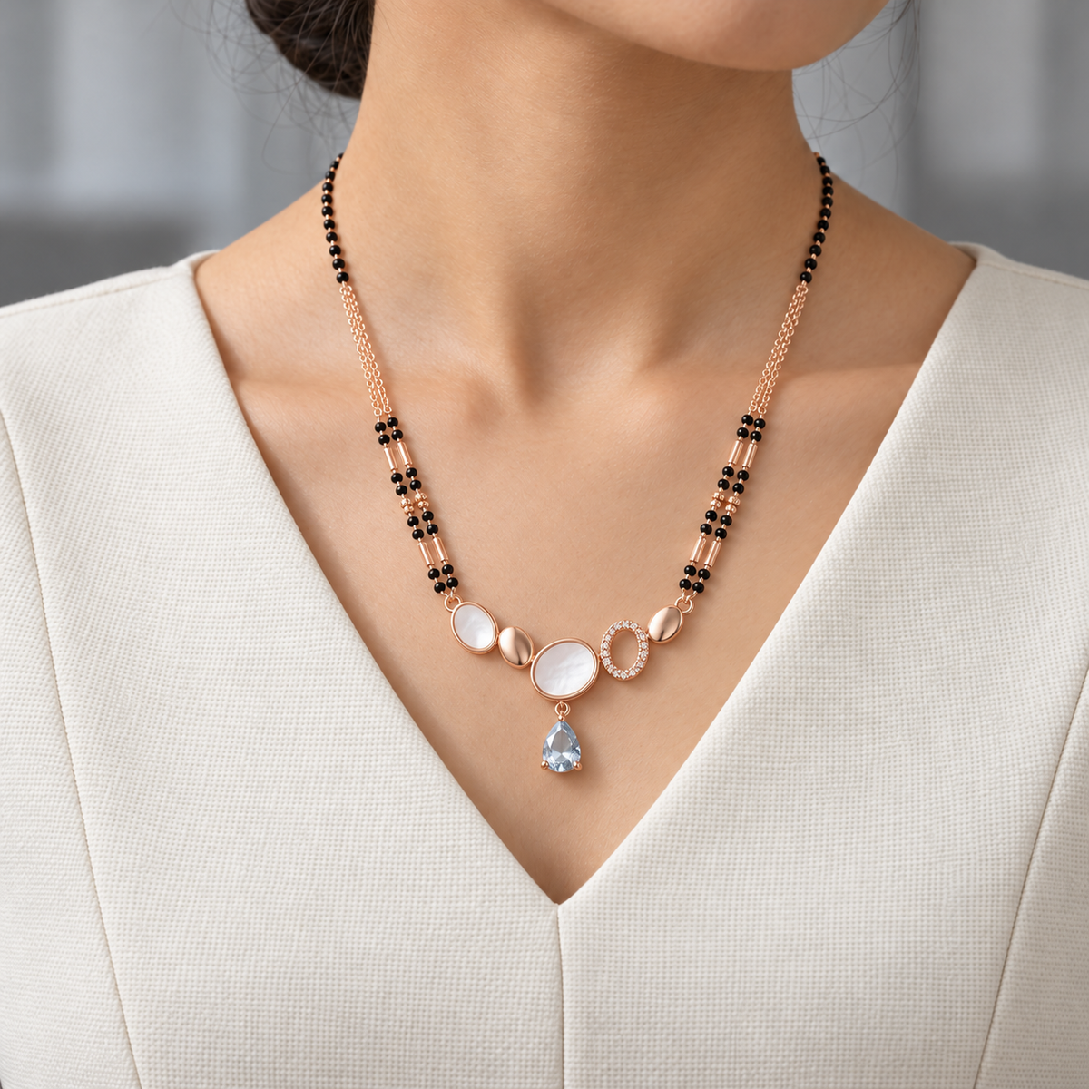 Odette Mangalsutra worn with an ivory woven V-neck dress, showing the pendant and black bead chain.