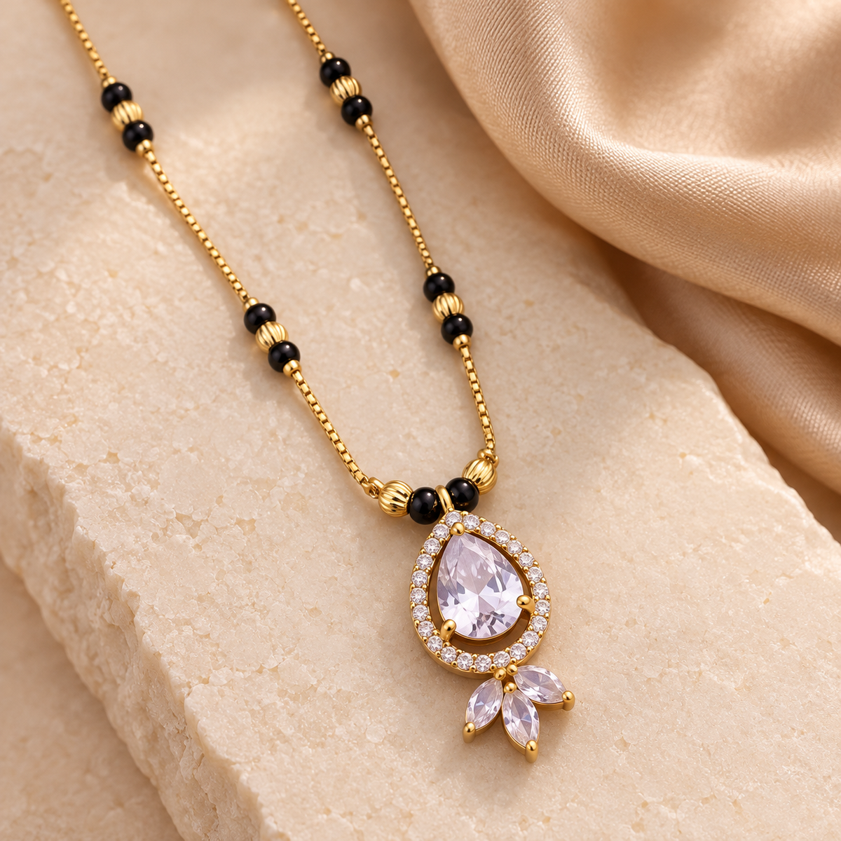 Close-up of Pallavi Mangalsutra's clear teardrop halo pendant, three marquise accents and black beads