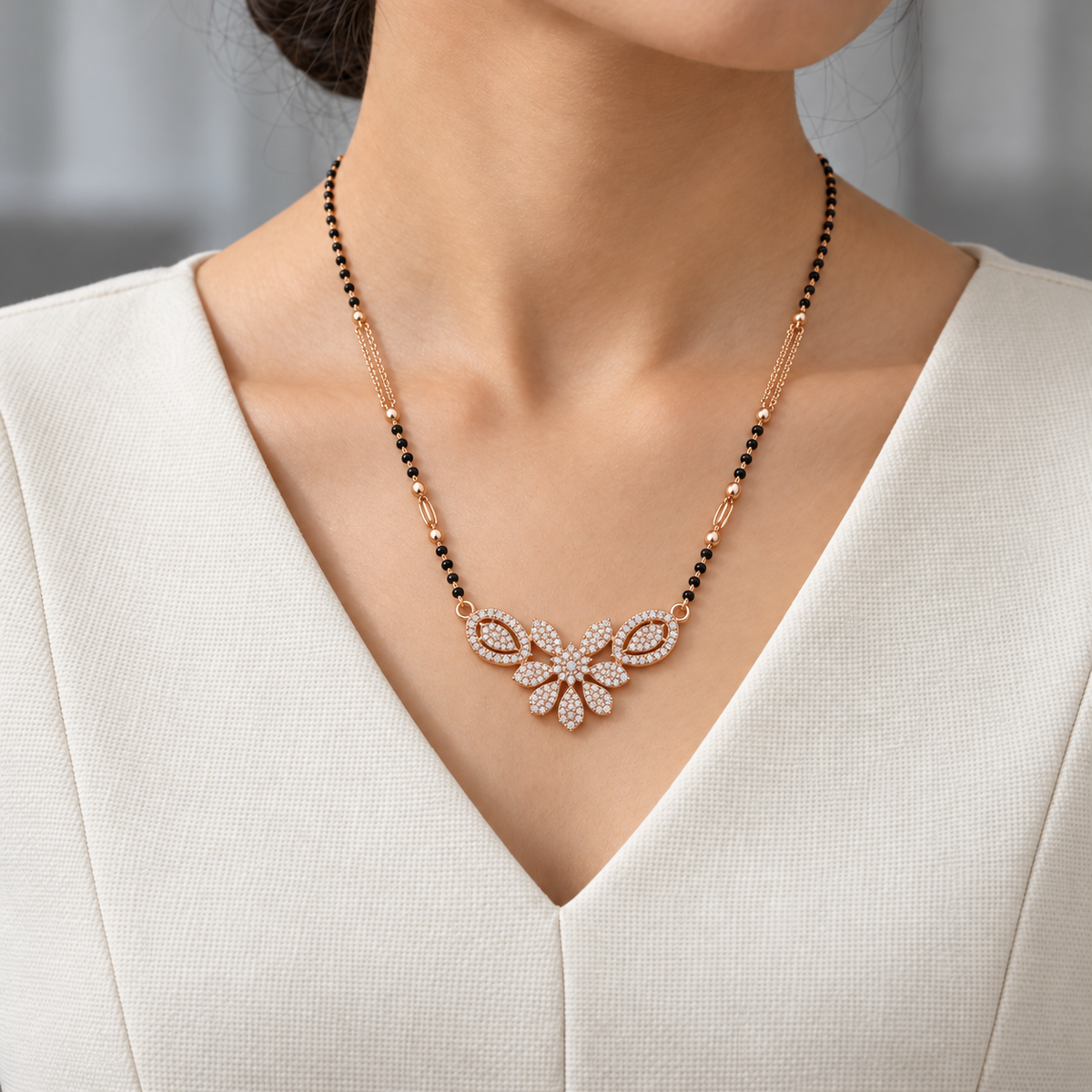 Rosamere Mangalsutra worn with an ivory woven V-neck dress, showing the pendant and black bead chain.
