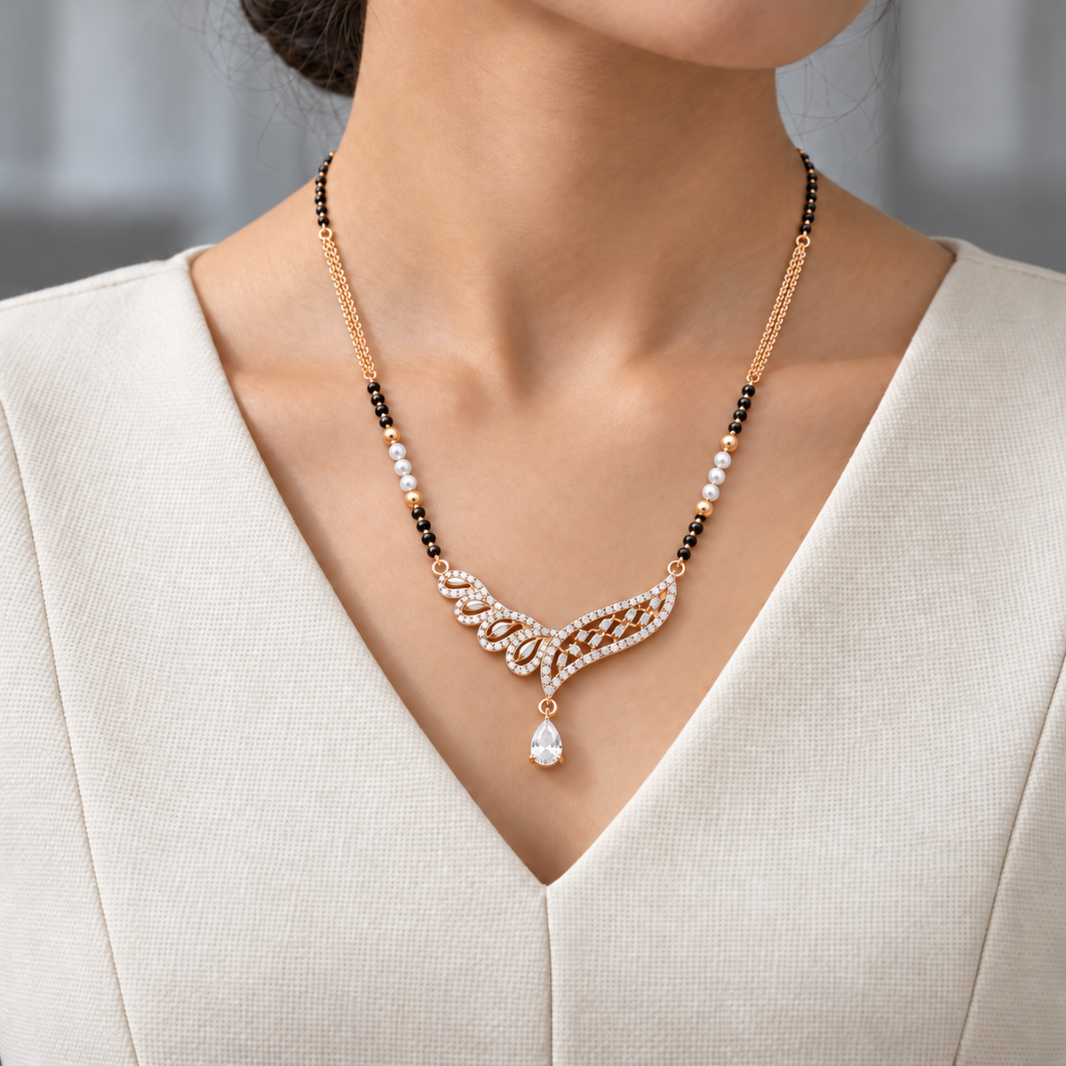 Solenne Mangalsutra worn with an ivory woven V-neck dress, showing the pendant and black bead chain.