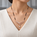 Sylvana Mangalsutra worn with an ivory woven V-neck dress, showing the pendant and black bead chain.