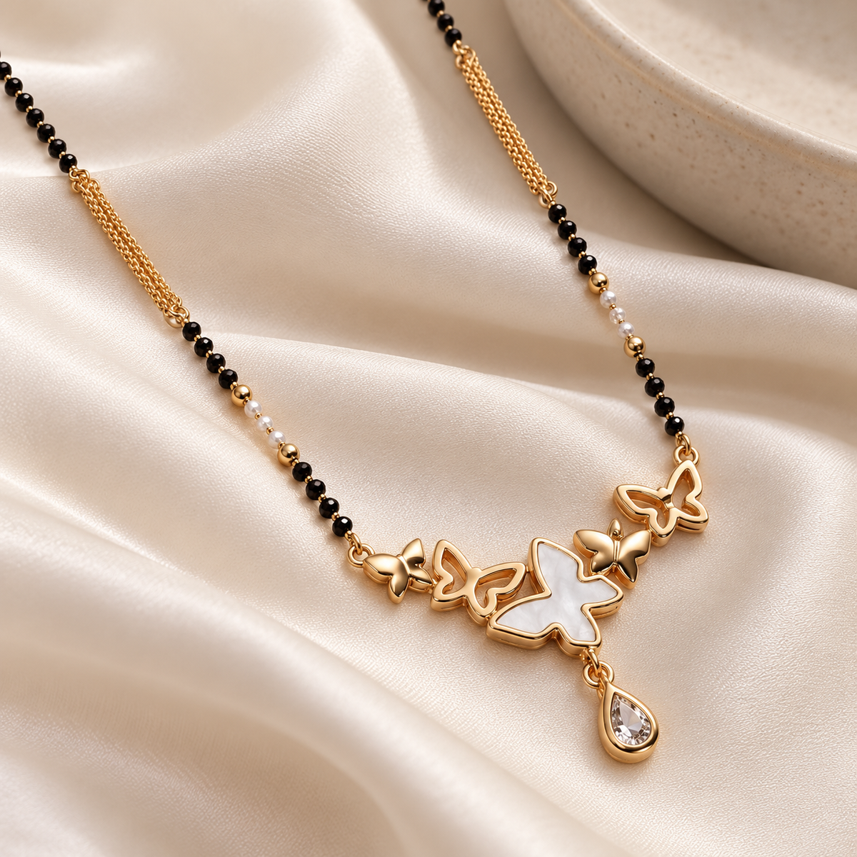 Close view of Vespera white-inlay butterfly and framed pear drop on ivory satin.