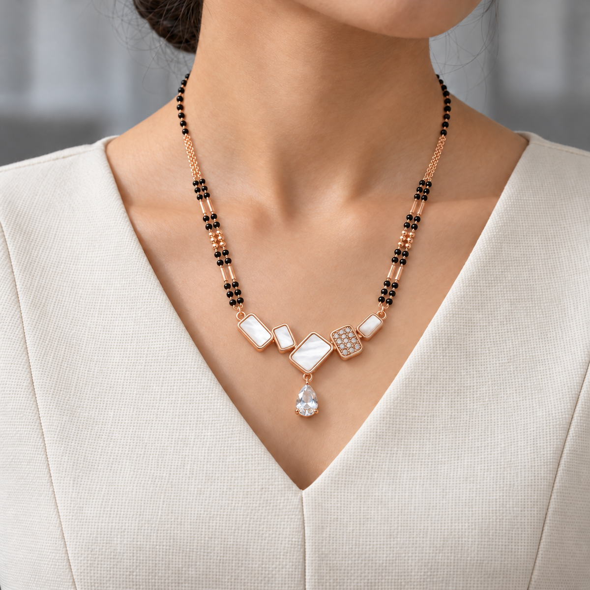 Vionne Mangalsutra worn with an ivory woven V-neck dress, showing the pendant and black bead chain.